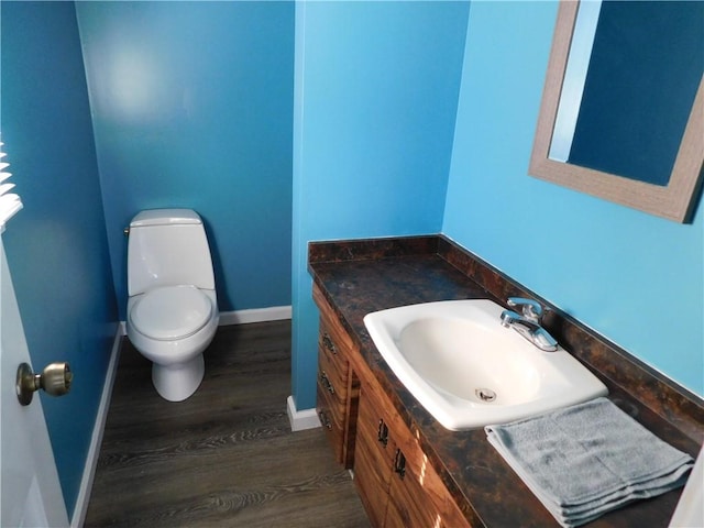 bathroom featuring baseboards, vanity, toilet, and wood finished floors