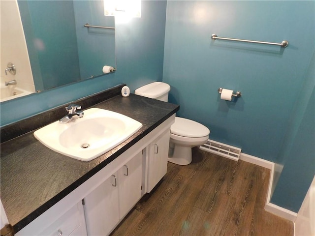 bathroom with visible vents, toilet, vanity, wood finished floors, and baseboards