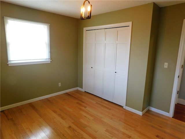 unfurnished bedroom featuring light wood-type flooring, a closet, and baseboards