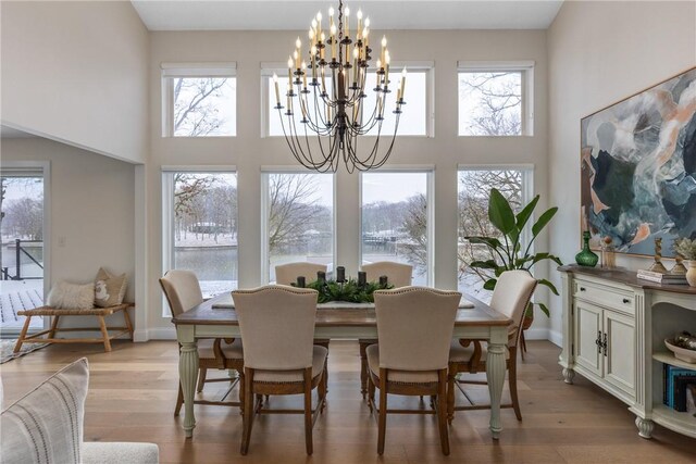 foyer entrance with high vaulted ceiling, wood-type flooring, and a chandelier