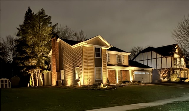 view of front of home with an attached garage, driveway, a yard, and a chimney
