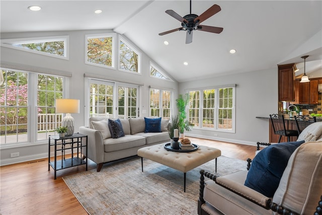 living area featuring ceiling fan, light wood-type flooring, high vaulted ceiling, baseboards, and recessed lighting