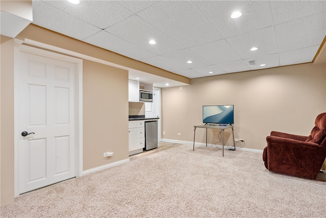 sitting room with light colored carpet, bar, baseboards, and a paneled ceiling