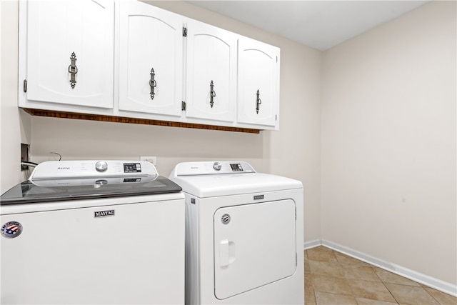 washroom featuring baseboards, cabinet space, light tile patterned flooring, and washing machine and clothes dryer