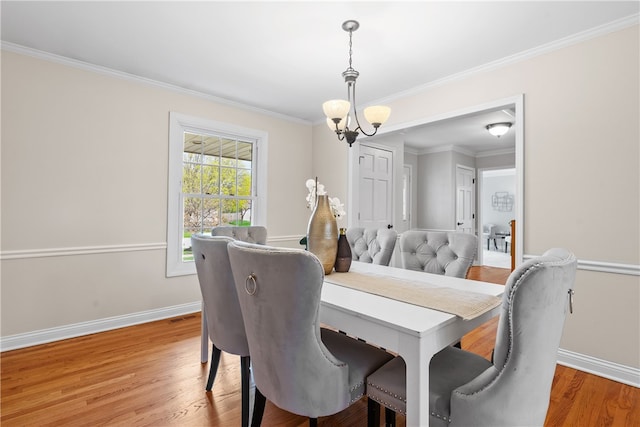 dining space with baseboards, crown molding, a chandelier, and light wood-type flooring
