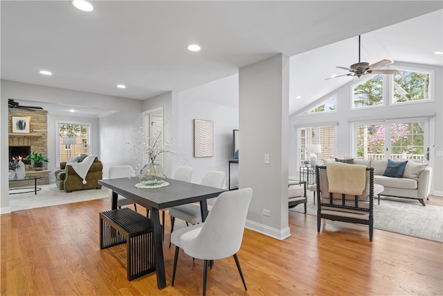 dining area with ceiling fan, light wood-style floors, a stone fireplace, recessed lighting, and baseboards