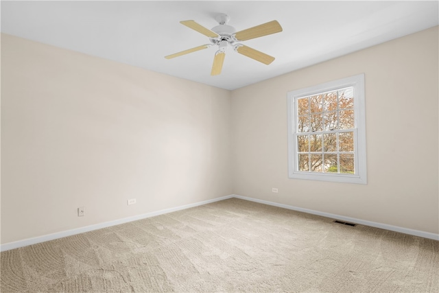 carpeted empty room with baseboards, visible vents, and ceiling fan