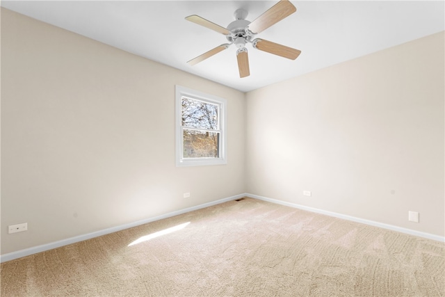 spare room with baseboards, a ceiling fan, and light colored carpet