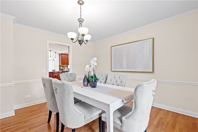 dining area featuring baseboards, ornamental molding, light wood-type flooring, and a chandelier