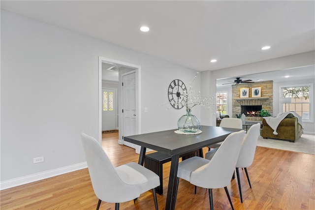 dining area featuring baseboards, plenty of natural light, a fireplace, and light wood-style flooring
