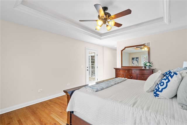bedroom featuring visible vents, a raised ceiling, baseboards, and light wood-style floors