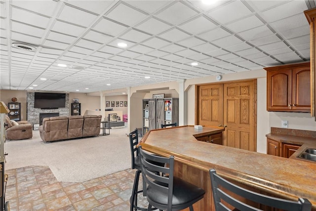 11154 E Ravenwood Ct, Effingham, IL 62401 - kitchen featuring a fireplace, a breakfast bar, brown cabinetry, recessed lighting, and light colored carpet