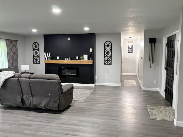 living room featuring recessed lighting, baseboards, a glass covered fireplace, and wood finished floors