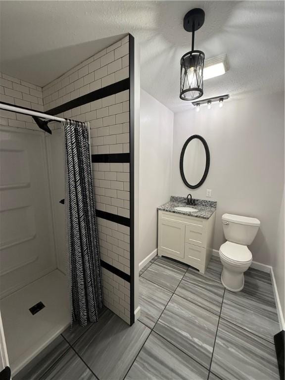 full bath with vanity, toilet, baseboards, a textured ceiling, and a shower stall