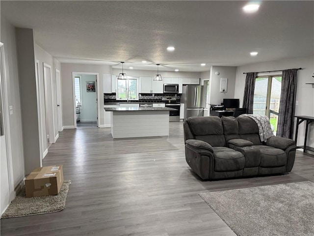 living room featuring a healthy amount of sunlight, baseboards, recessed lighting, and light wood-style flooring