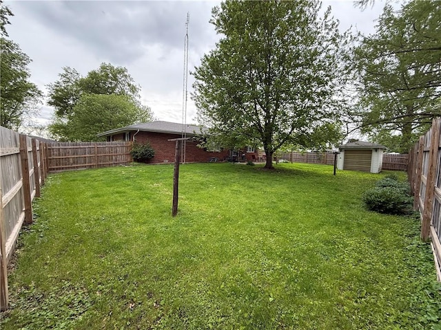view of yard featuring an outbuilding, a fenced backyard, and a storage unit