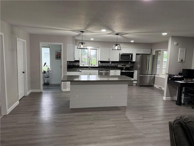 kitchen featuring decorative backsplash, appliances with stainless steel finishes, a sink, baseboards, and white cabinets