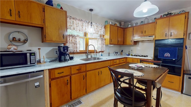 714 Parras St, Danville, IL 61832 - kitchen featuring stainless steel appliances, under cabinet range hood, brown cabinetry, light countertops, and a warming drawer