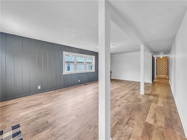 basement featuring a textured ceiling, baseboards, and wood finished floors