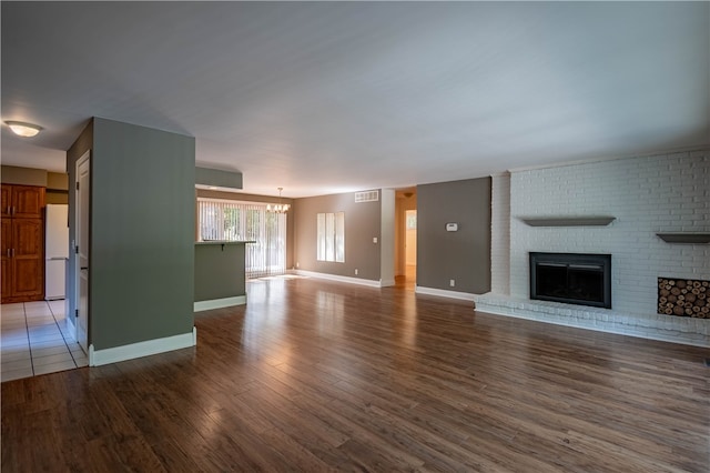 unfurnished living room featuring a fireplace, wood-type flooring, and a notable chandelier