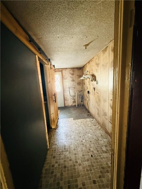 corridor with wood walls and a barn door