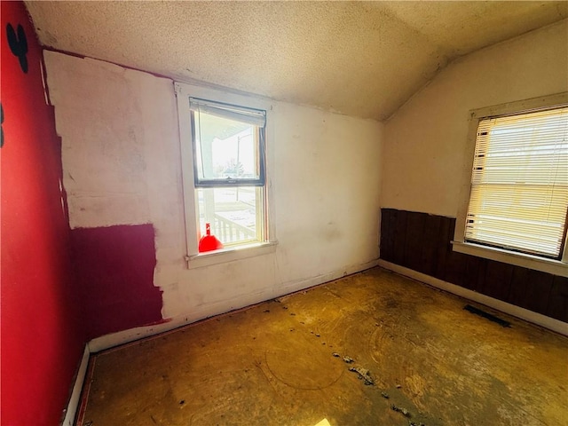 spare room featuring a textured ceiling and lofted ceiling