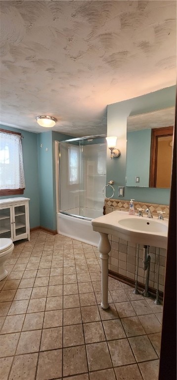 bathroom featuring toilet, tile patterned floors, and bath / shower combo with glass door