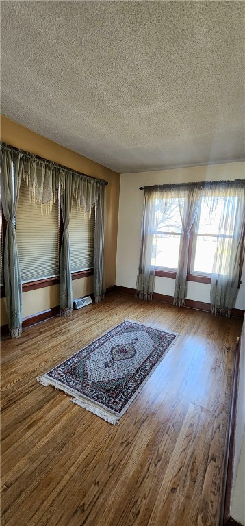 unfurnished room featuring hardwood / wood-style flooring and a textured ceiling