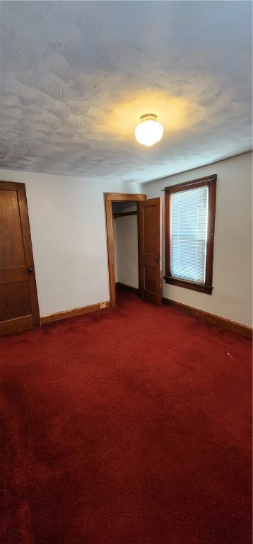 spare room with dark carpet and a textured ceiling