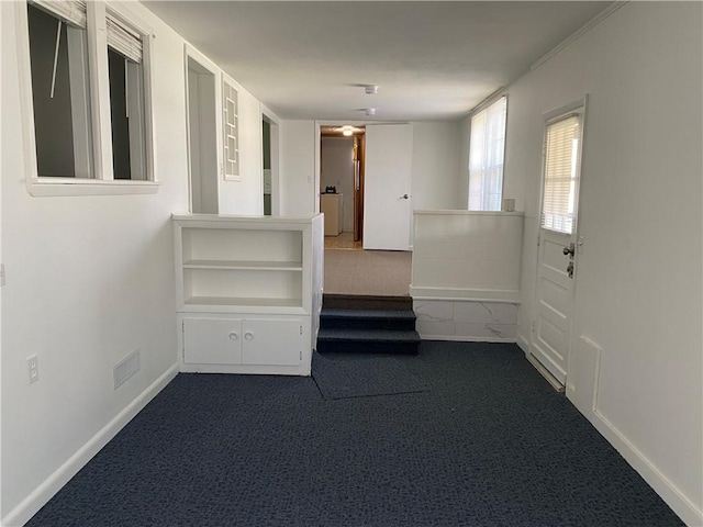 spare room featuring dark colored carpet, washer / clothes dryer, visible vents, and baseboards