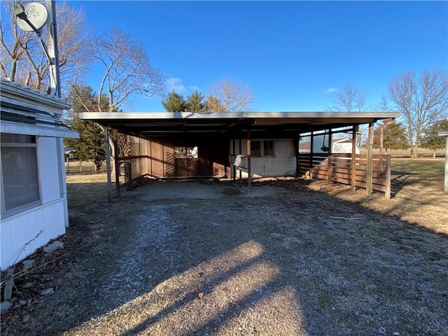 exterior space with driveway, an attached carport, and an outdoor structure