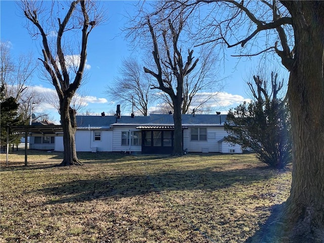 back of property with an attached garage, a sunroom, and a yard