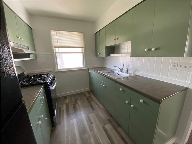 kitchen featuring green cabinets, wood finished floors, a sink, and black gas stove