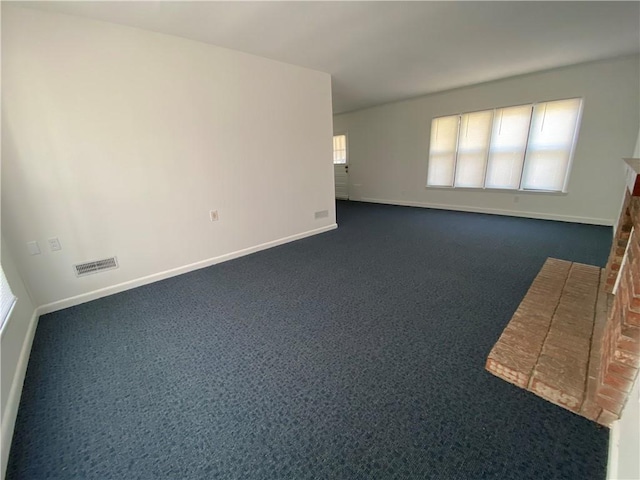 empty room with dark colored carpet, visible vents, and baseboards