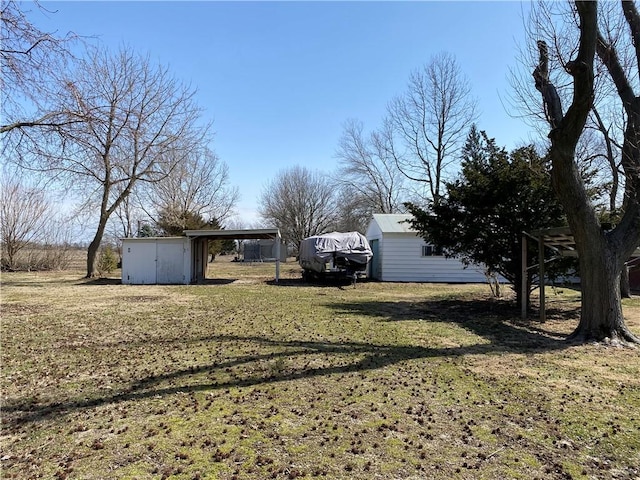 view of yard with a storage shed, a carport, and an outdoor structure