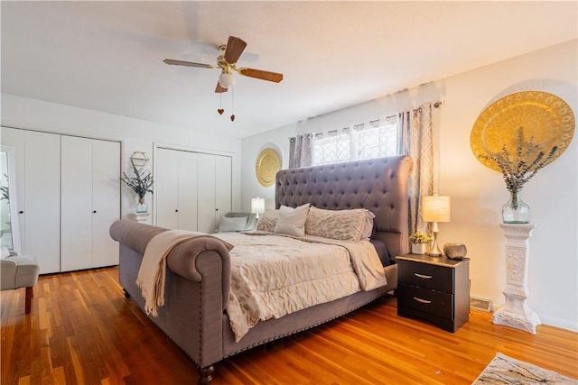 bedroom featuring wood finished floors, multiple closets, and ceiling fan