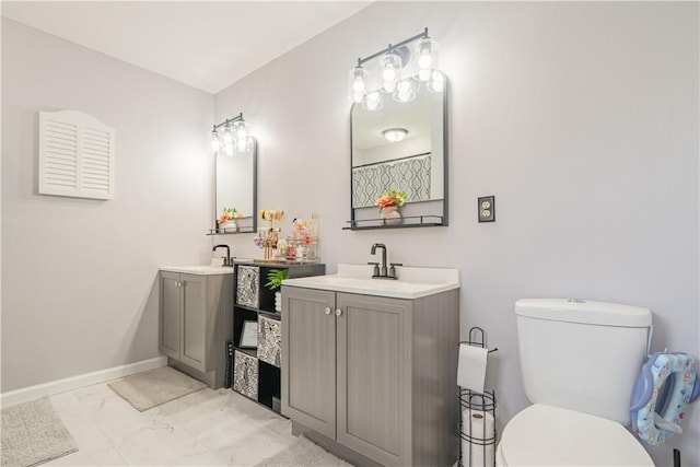 bathroom with two vanities, a sink, toilet, baseboards, and marble finish floor