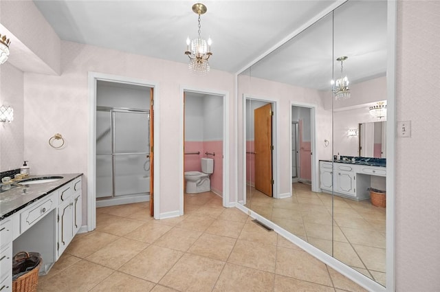 full bathroom featuring a chandelier, tile patterned flooring, toilet, and vanity