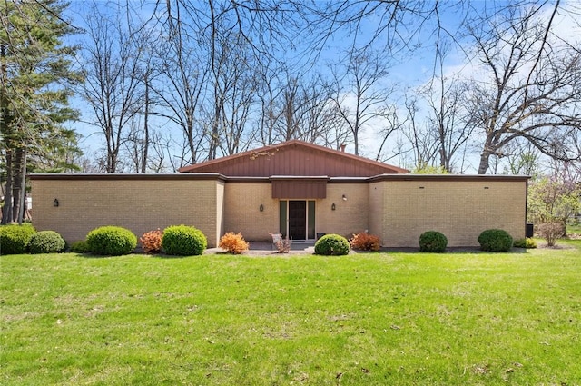 view of front of house with brick siding, a front yard, and board and batten siding