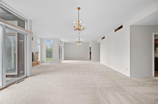 carpeted empty room with a chandelier, a brick fireplace, and baseboards