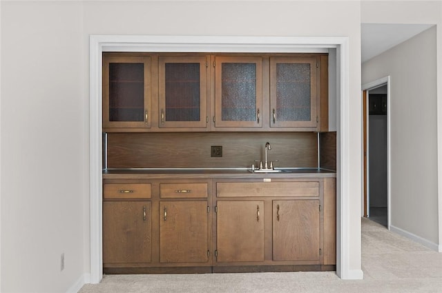 indoor wet bar featuring baseboards and light carpet