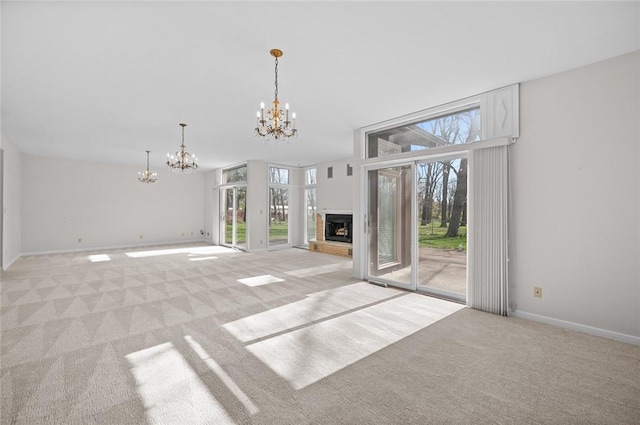 unfurnished living room featuring light colored carpet, a chandelier, baseboards, and a brick fireplace