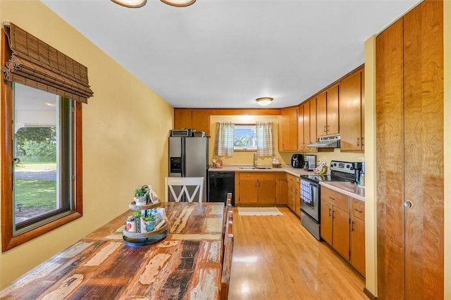 1283 N 1400 E Rd, Shelbyville, IL 62565 - kitchen with appliances with stainless steel finishes, under cabinet range hood, a sink, light countertops, and light wood-style floors