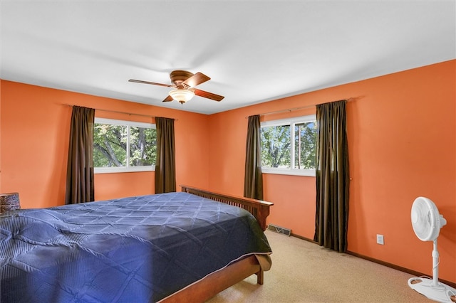 carpeted bedroom with multiple windows and ceiling fan