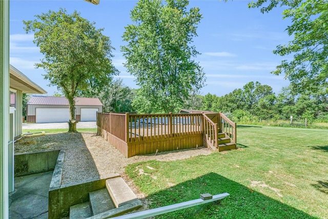 view of yard with a garage, an outbuilding, and a wooden deck