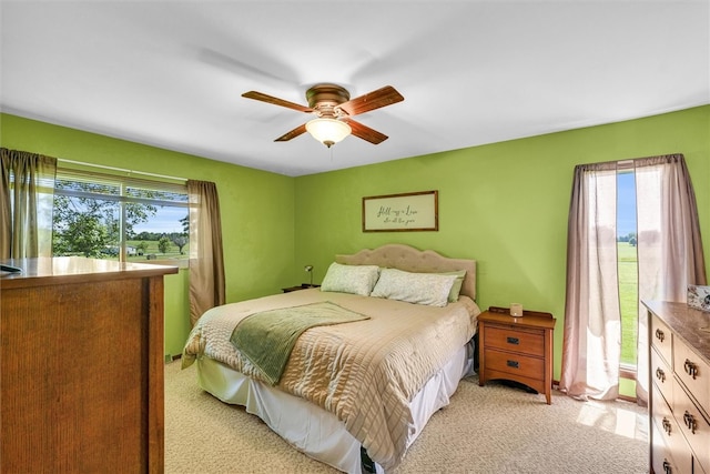 carpeted bedroom featuring multiple windows and ceiling fan