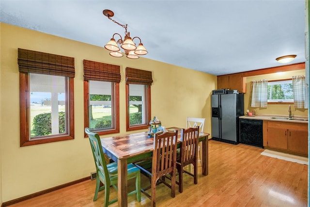 dining area featuring a wealth of natural light, sink, an inviting chandelier, and light hardwood / wood-style flooring