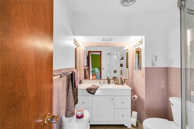 bathroom with vanity, a shower with door, toilet, and tile walls