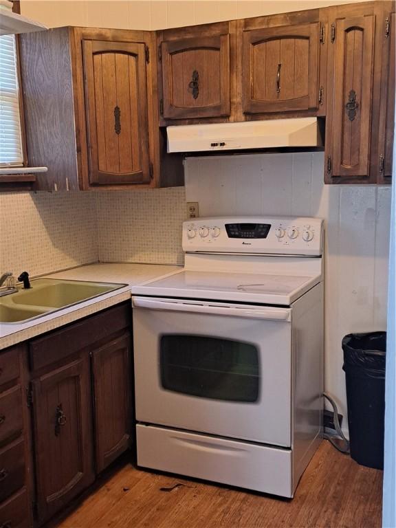 508 S Webster St, Robinson, IL 62454 - kitchen featuring white electric range, extractor fan, light countertops, light wood-type flooring, and decorative backsplash