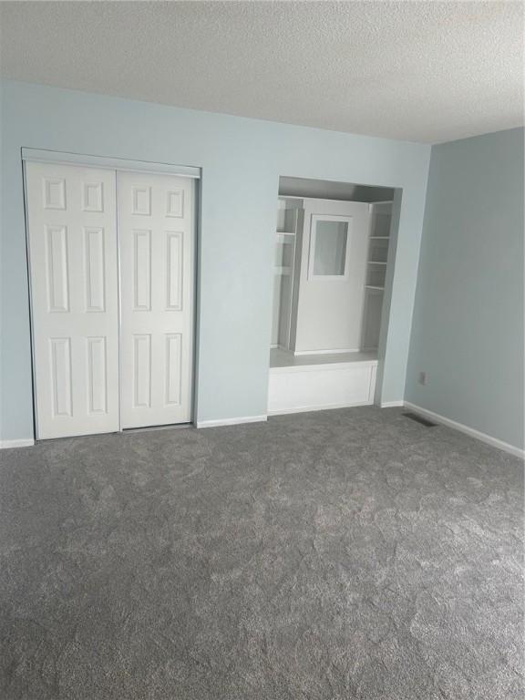202 S 4th St, Marshall, IL 62441 - unfurnished bedroom featuring carpet floors, a textured ceiling, and a closet